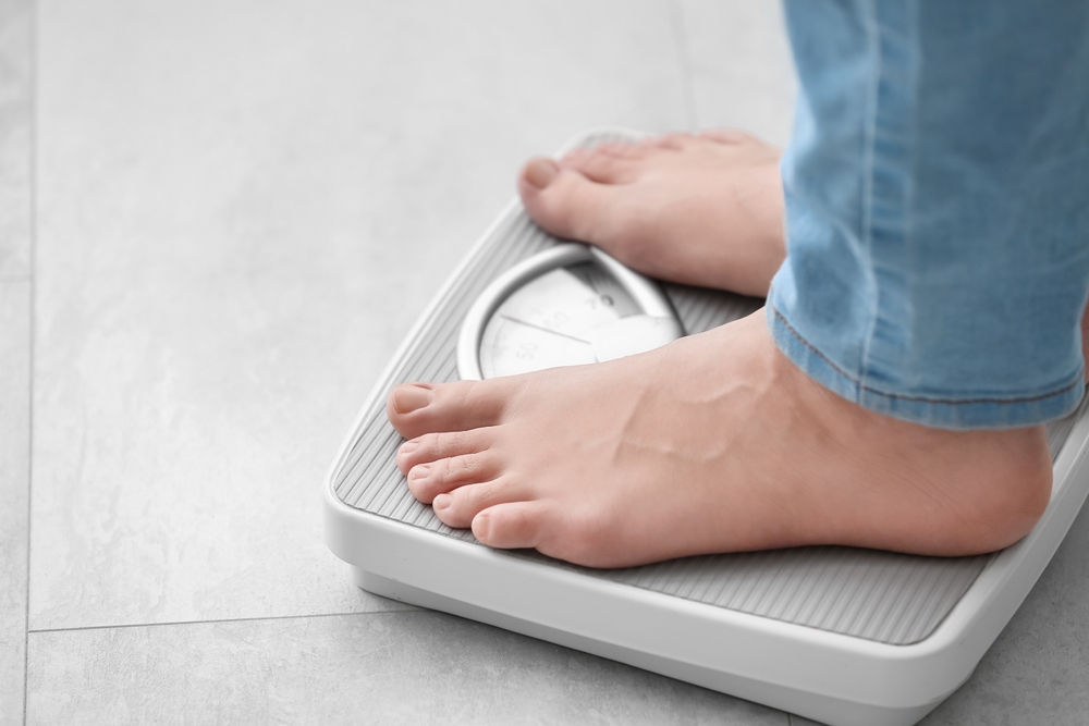 person's feet standing on a weight scale